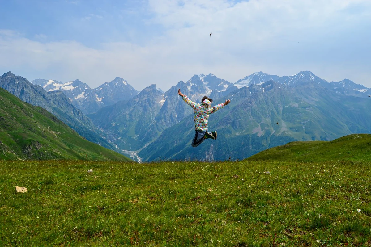 Hiker celebrating on Svaneti mountain ridge with panoramic Caucasus views