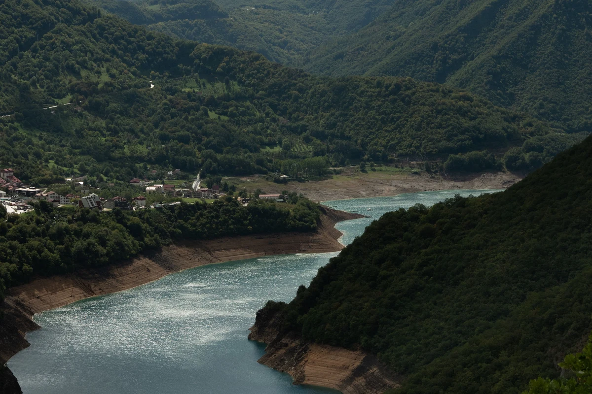 River winding through a lush forested mountain valley in the Caucasus — the dense woodland terrain hikers pass through in Lagodekhi National Park on the route to Black Rock Lake