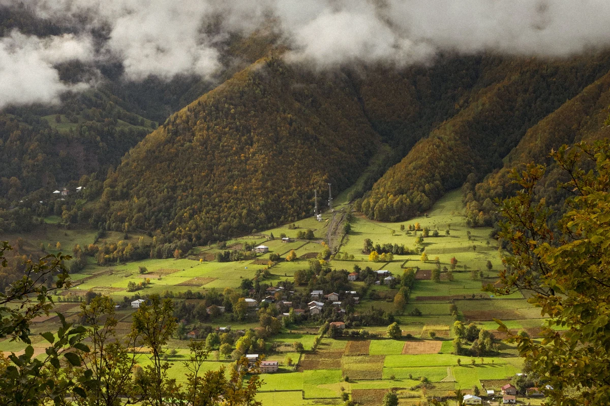 Aerial view of a traditional village surrounded by lush green mountain slopes in Racha region, Georgia — near the trailhead for the Udziro Lake trek