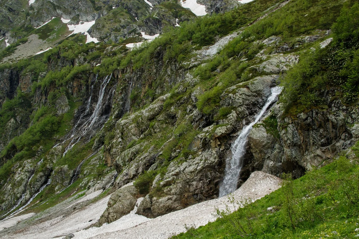 Shdugra Waterfall dropping through rocky Caucasus terrain and lush greenery