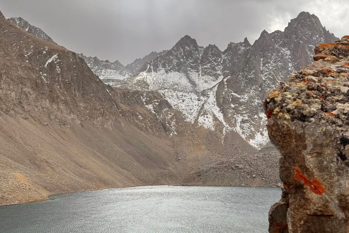 Serene mountain lake surrounded by rugged peaks under dramatic clouds at Tobavarchkhili